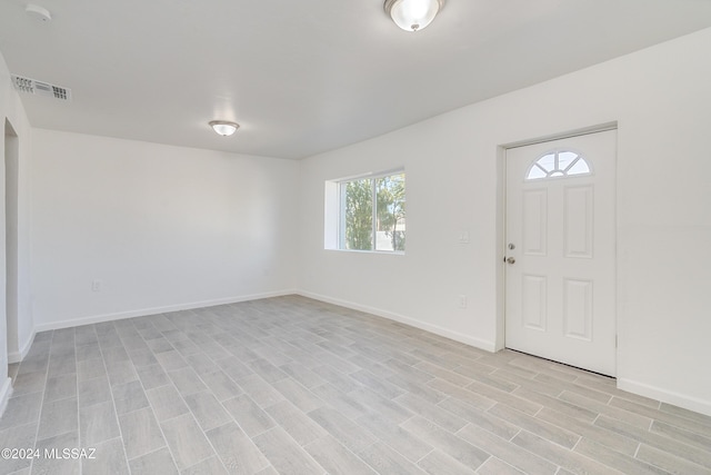 foyer entrance featuring light wood-style floors, visible vents, and baseboards