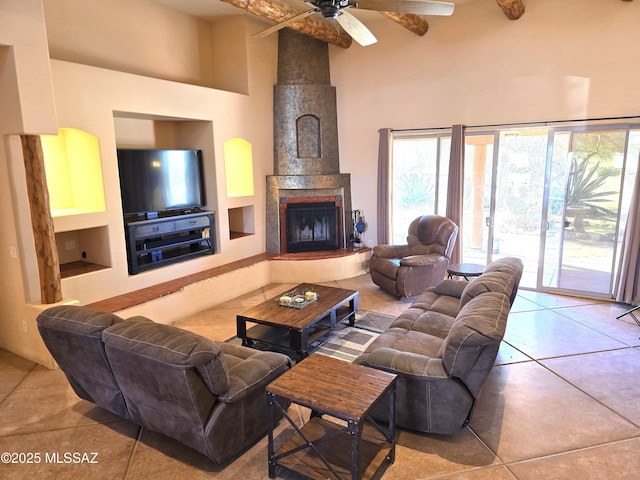 living room with ceiling fan, built in shelves, light tile patterned floors, and a towering ceiling
