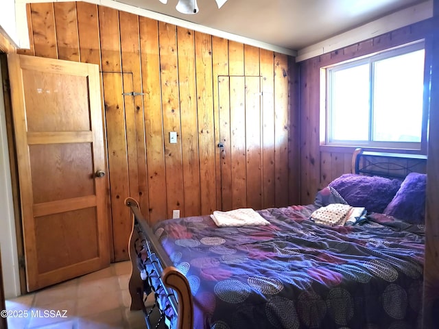 bedroom with light tile patterned floors and wood walls
