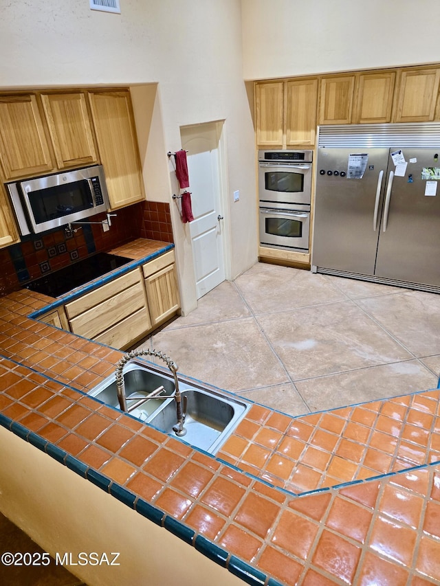 kitchen with sink, light tile patterned floors, stainless steel appliances, and tile countertops