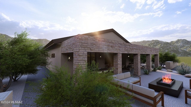 rear view of property featuring a mountain view and an outdoor living space with a fire pit