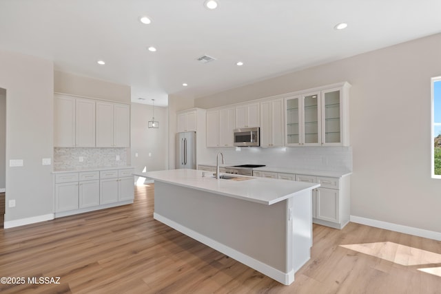 67620 E Lauren Pl, Oracle, AZ 85623 - kitchen with appliances with stainless steel finishes, a sink, decorative backsplash, a kitchen island with sink, and white cabinetry