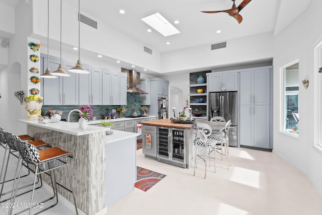 kitchen featuring stainless steel appliances, wall chimney range hood, backsplash, pendant lighting, and a breakfast bar