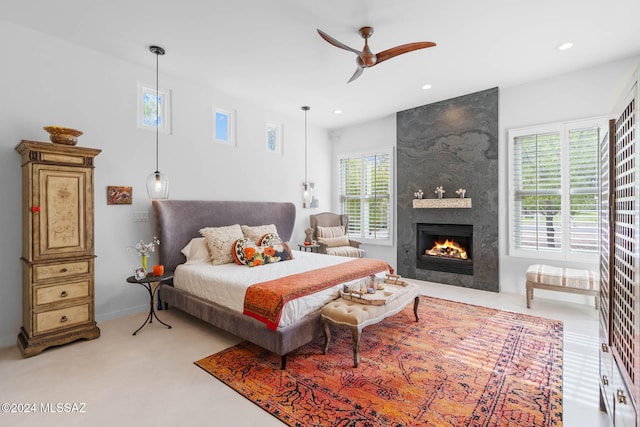 bedroom featuring a large fireplace and ceiling fan