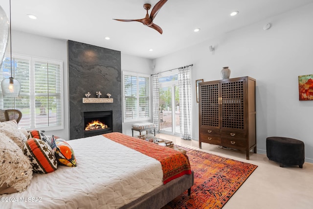 bedroom with a fireplace, ceiling fan, light carpet, and access to exterior