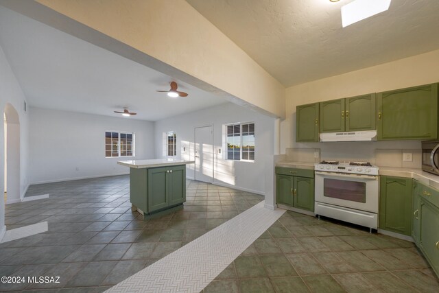 kitchen with kitchen peninsula, white range, dark tile patterned floors, ceiling fan, and green cabinetry