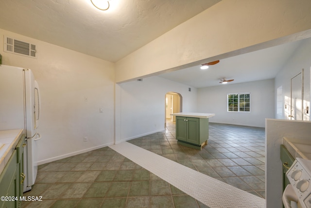 kitchen featuring dark tile patterned floors, ceiling fan, white refrigerator, washer / dryer, and green cabinets