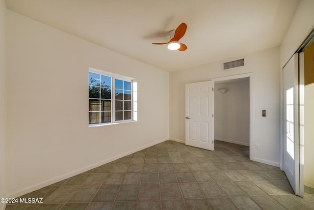 empty room with ceiling fan and light tile patterned flooring