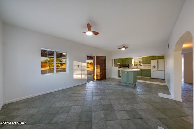 unfurnished living room featuring ceiling fan and dark tile patterned floors