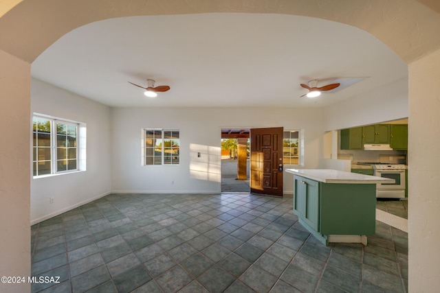 kitchen with dark tile patterned flooring, ceiling fan, green cabinets, and white range with gas cooktop