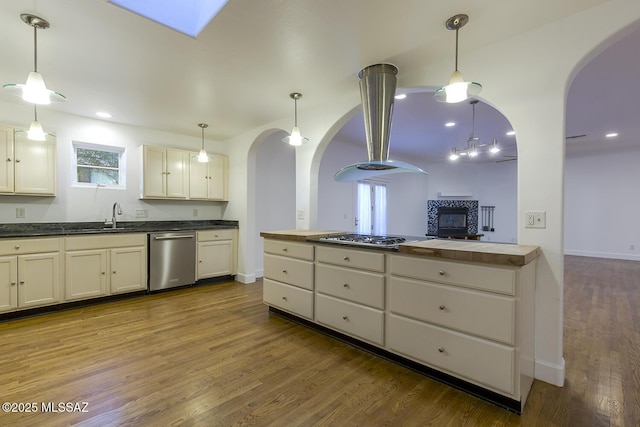 kitchen with pendant lighting, a sink, wood finished floors, arched walkways, and appliances with stainless steel finishes