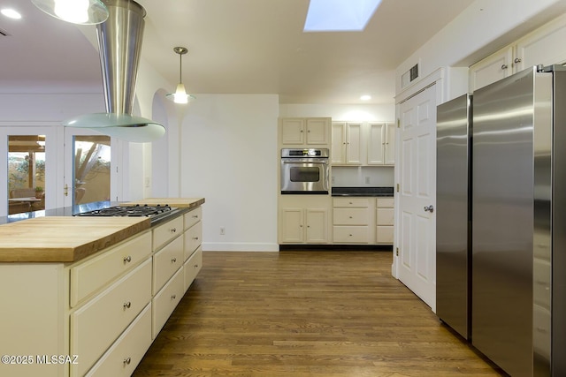 kitchen with visible vents, butcher block countertops, dark wood finished floors, stainless steel appliances, and a skylight