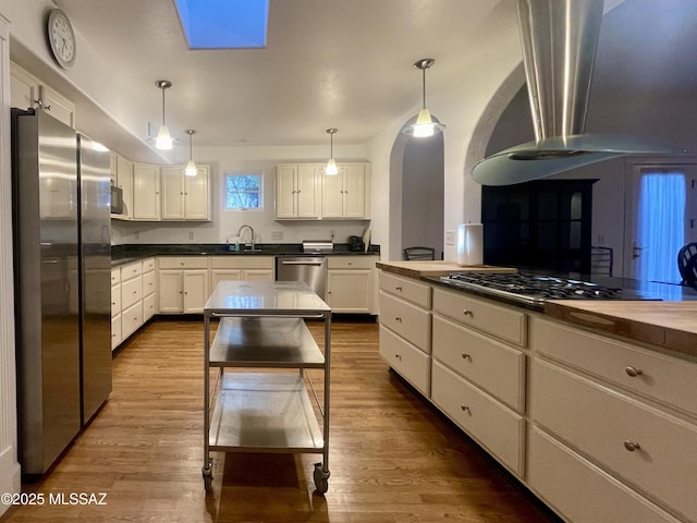 kitchen with dark wood-style flooring, a sink, white cabinets, appliances with stainless steel finishes, and pendant lighting