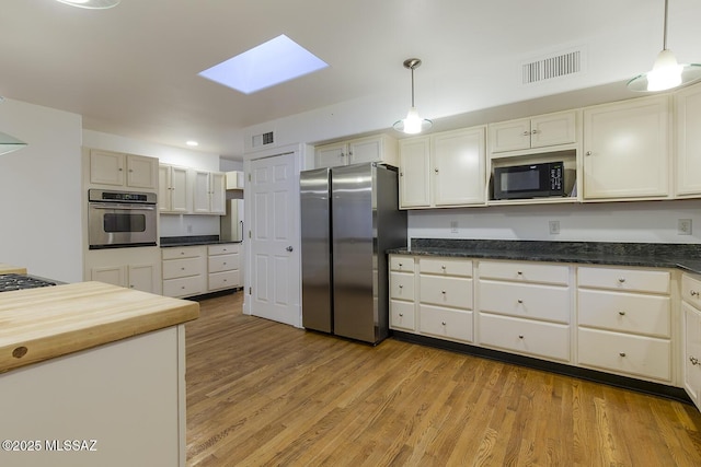 kitchen featuring decorative light fixtures, stainless steel appliances, light wood-style floors, and visible vents