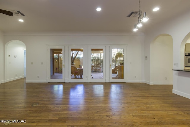 unfurnished living room with wood finished floors, recessed lighting, arched walkways, and visible vents