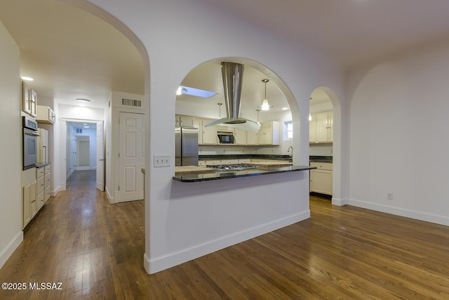 kitchen with visible vents, dark wood-type flooring, dark countertops, stainless steel appliances, and arched walkways