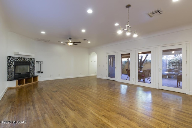 unfurnished living room with a tiled fireplace, visible vents, and wood finished floors