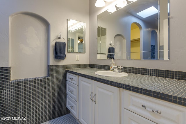 bathroom with a wainscoted wall, tile walls, and vanity