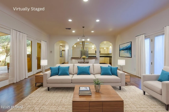 living room featuring recessed lighting, visible vents, arched walkways, and wood finished floors