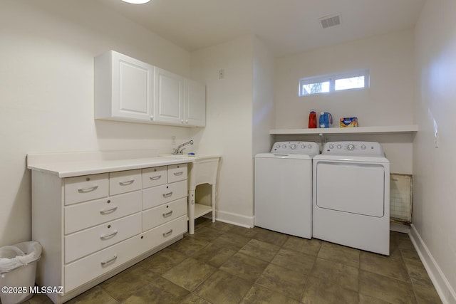 clothes washing area featuring washer and clothes dryer, visible vents, cabinet space, and baseboards