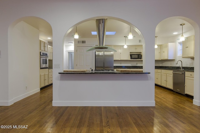 kitchen with visible vents, a sink, dark countertops, dark wood-style floors, and stainless steel appliances