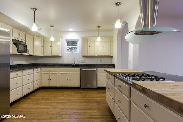 kitchen with wall chimney exhaust hood, dark wood-style flooring, appliances with stainless steel finishes, and pendant lighting