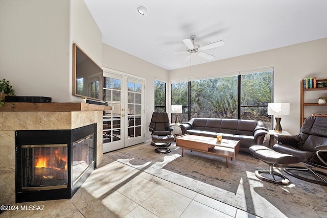 living room with a tile fireplace, ceiling fan, and french doors