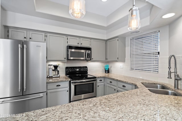 kitchen with pendant lighting, backsplash, a raised ceiling, sink, and stainless steel appliances