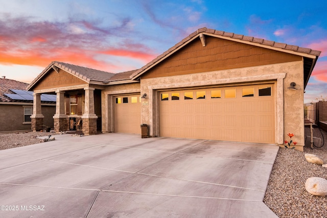 view of front facade featuring driveway, an attached garage, a tiled roof, and stucco siding