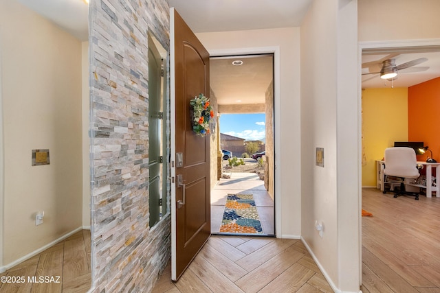 foyer entrance with a ceiling fan, light wood-type flooring, and baseboards