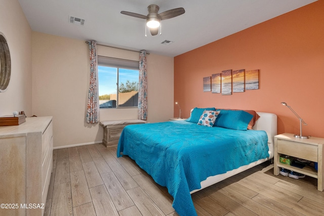 bedroom with ceiling fan, light wood-type flooring, visible vents, and baseboards