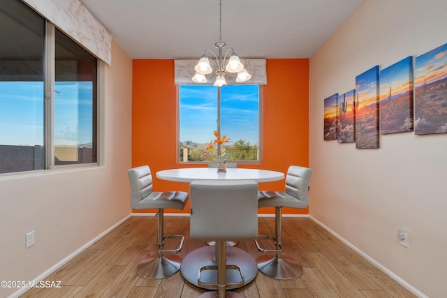 dining area with a chandelier, baseboards, and wood tiled floor