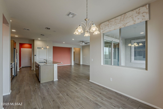 kitchen with visible vents, freestanding refrigerator, ceiling fan with notable chandelier, and open floor plan