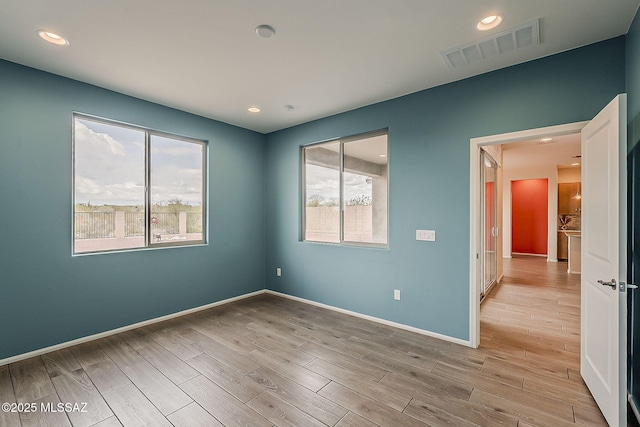 unfurnished room with baseboards, a healthy amount of sunlight, light wood finished floors, and visible vents