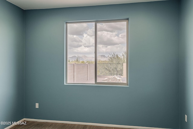 empty room with baseboards and wood finished floors