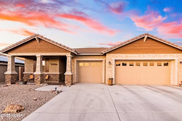 view of front of house featuring an attached garage, driveway, a tile roof, and stucco siding