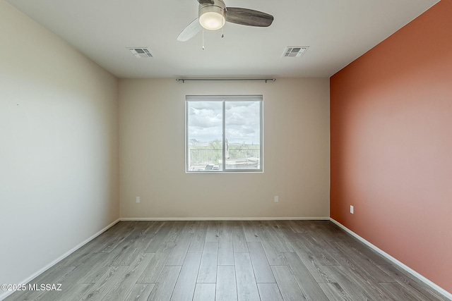 empty room featuring a ceiling fan, wood finished floors, baseboards, and visible vents