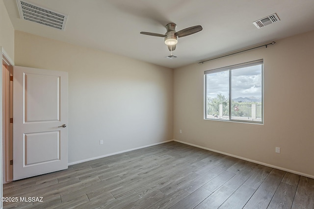 empty room featuring a ceiling fan, wood finished floors, and visible vents