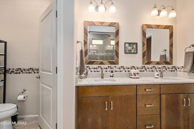 full bath with double vanity, toilet, a sink, and tiled shower