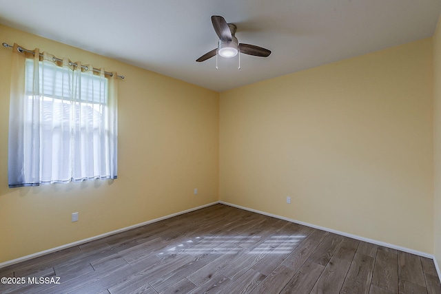 spare room with baseboards, wood finished floors, and a ceiling fan