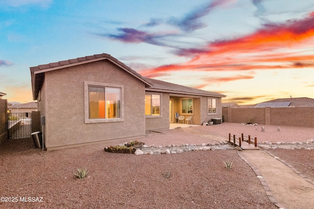 rear view of property featuring a patio area, a fenced backyard, and stucco siding