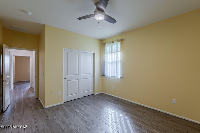 unfurnished bedroom featuring a closet, visible vents, baseboards, wood finished floors, and a ceiling fan
