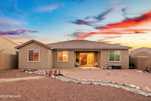 rear view of house featuring a patio area, a fenced backyard, a tiled roof, and stucco siding