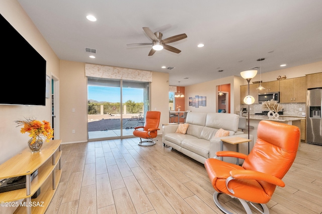 living room with light wood finished floors, visible vents, baseboards, ceiling fan, and recessed lighting