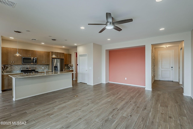 kitchen with visible vents, light wood-style flooring, ceiling fan, appliances with stainless steel finishes, and open floor plan