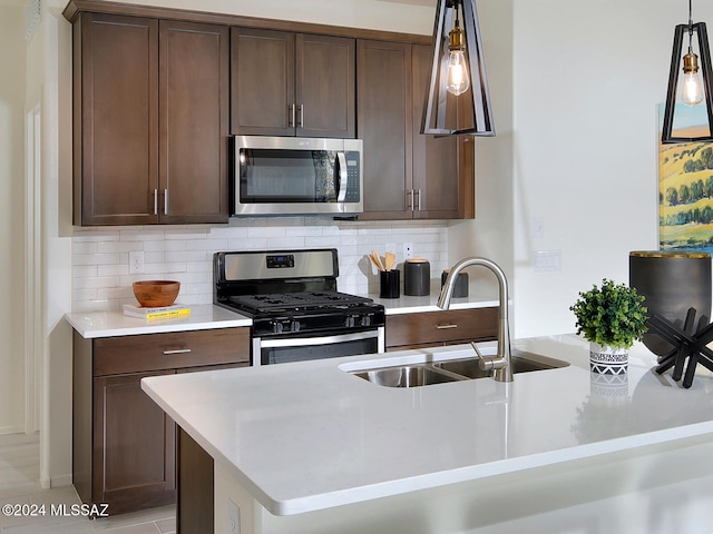 kitchen with appliances with stainless steel finishes, backsplash, dark brown cabinets, and sink