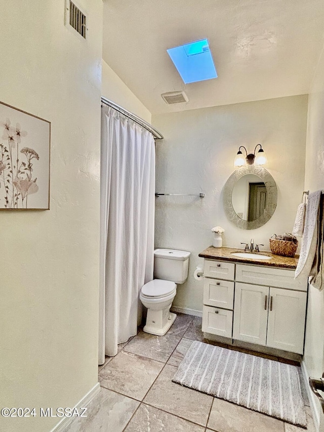 bathroom with vanity, a shower with curtain, vaulted ceiling with skylight, tile patterned flooring, and toilet