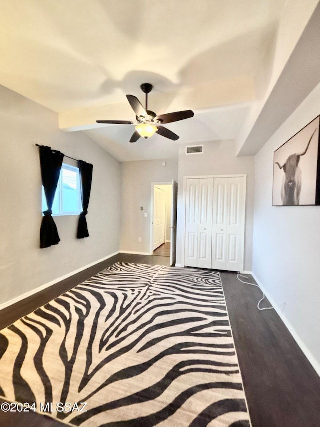 bedroom with ceiling fan, dark hardwood / wood-style floors, vaulted ceiling, and a closet