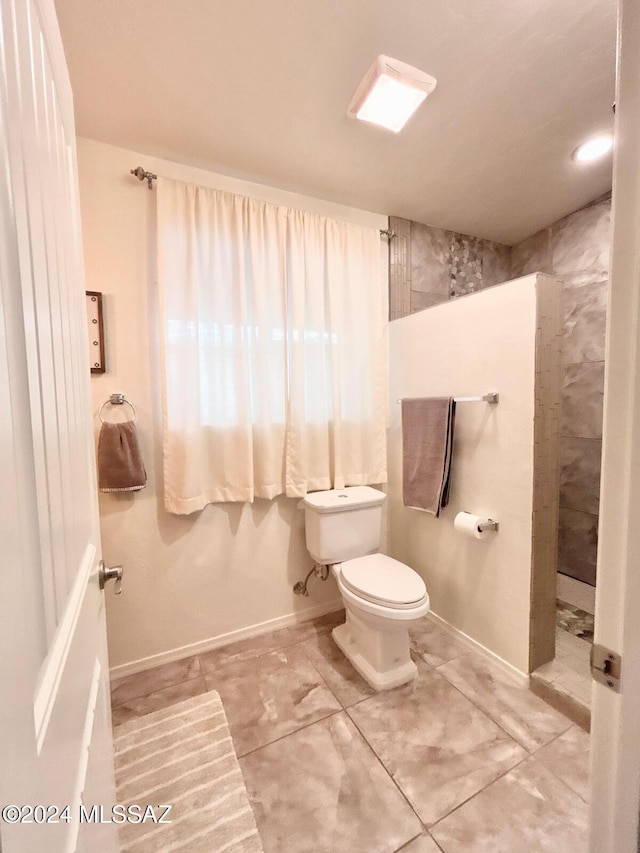 bathroom with a tile shower and toilet