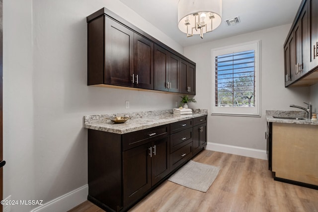 washroom featuring sink, light hardwood / wood-style floors, and a notable chandelier